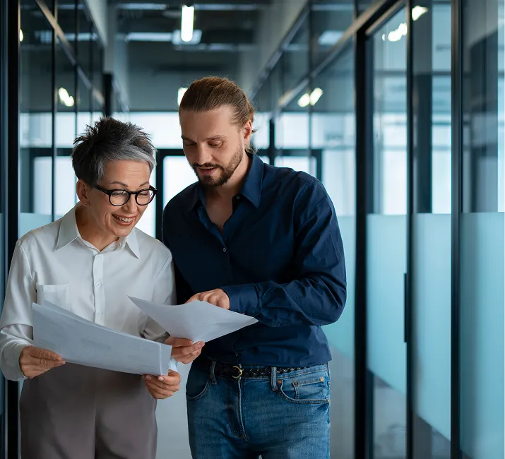 Two colleagues reviewing printed documents in an office